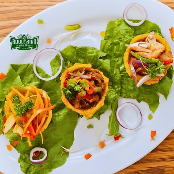 Three Haitian tostones filled with various meats and vegetables, garnished with lettuce and onion rings.