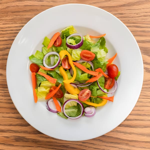 Fresh Haitian garden salad with lettuce, tomatoes, red onions, carrots, and yellow bell peppers.