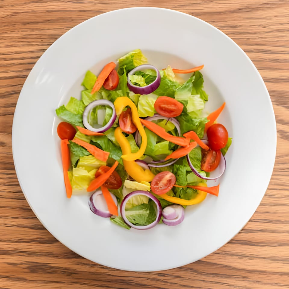Fresh Haitian garden salad with lettuce, tomatoes, red onions, carrots, and yellow bell peppers.