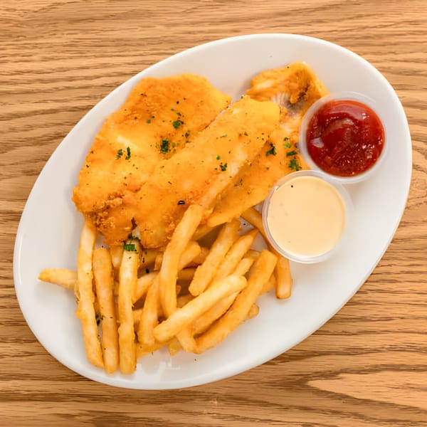 Golden-fried fish and french fries with ketchup and a creamy dipping sauce on a white plate.